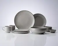 Et sæt stentøj i en blød grå farve med en let ujævn glasur. Sættet indeholder store middagstallerkener, mindre frokosttallerkener, dybe skåle, en lille skål og krus. Hver del har et minimalistisk design med glatte, afrundede kanter og en tynd, mørkere kant, der fremhæver formen. Udtrykket er moderne og enkelt, velegnet til både hverdags- og festbrug.