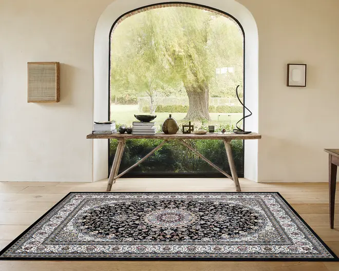 Rektangulært tæppe med et traditionelt persisk-inspireret design, der har et centralt medaljonmønster i nuancer af bordeaux, creme og blå, omgivet af indviklede blomster- og vinmotiver. Tæppet har en mørk baggrund med en detaljeret kant i lysere farver og en lav luv, der egner sig til områder med meget trafik. Kanterne er pænt afsluttede, og det samlede udtryk er elegant og klassisk, hvilket passer til både moderne og traditionelle indretninger.