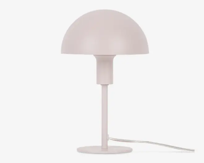 En moderne bordlampe med mat, lyserød overflade. Lampen har en kuppelformet skærm, en slank cylindrisk stang og en rund, flad fod. Designet er minimalistisk med rene linjer, og en hvid ledning er synlig fra lampens fod.