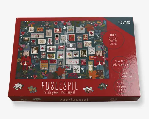 Æsken har et festligt design med et patchwork af små, farverige firkanter, der hver indeholder forskellige julemotiver som nøddeknækkere, hjerter, stjerner og juletræer. Baggrunden er dekoreret med kristtorn, bær og blade, hvilket giver et hyggeligt, sæsonpræget udtryk. Æsken angiver, at puslespillet indeholder 1000 brikker og er egnet til hele familien. Emballagen er overvejende rød med dekorative elementer og tydelig mærkning på flere sprog.