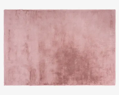 Rektangulært tæppe med en blød, plysset tekstur og en ensartet støvet rosa farve. Overfladen fremstår fløjlsagtig og let skinnende, hvilket giver et luksuriøst udtryk. Kanterne er pænt afsluttede, og luven er tæt, hvilket giver en behagelig og hyggelig fornemmelse under fødderne.