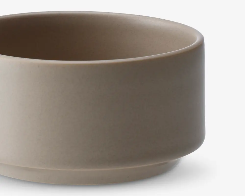 En minimalistisk, rund skål med en glat, mat beige overflade. Skålen har lige sider og en let hævet bund, hvilket giver et moderne og enkelt udtryk. Både inderside og yderside har samme farve, og kanten er blødt afrundet for et elegant udseende.