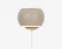 En moderne væglampe med en glat, rund skærm i mat beige. Lampen har et minimalistisk design, hvor lyset rettes nedad fra den åbne bund af skærmen. Den er monteret med en hvid ledning, der går ud fra bunden, og det samlede udtryk er stilrent og nutidigt, hvilket passer til mange forskellige indretninger.
