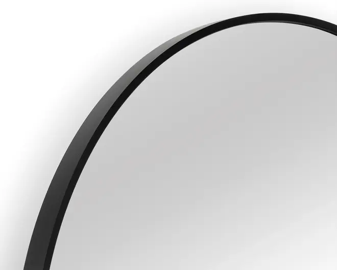 Nærbillede af et rundt spejl med en tynd, mat sort metalramme. Rammen har en glat overflade og et moderne, minimalistisk design.