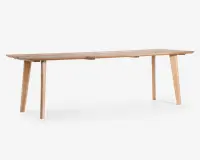 Rektangulært bord i lyst træ med en naturlig finish. Bordet har et minimalistisk design med rene linjer og fire let skråtstillede ben for stabilitet. Bordpladen er glat og flad med synlig træstruktur, og det overordnede udtryk er moderne og enkelt, velegnet til spise- eller arbejdsbrug.