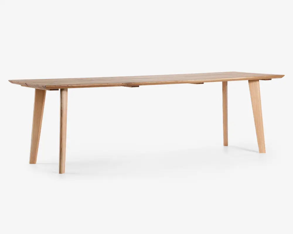 Rektangulært bord i lyst træ med en naturlig finish. Bordet har et minimalistisk design med rene linjer og fire let skråtstillede ben for stabilitet. Bordpladen er glat og flad med synlig træstruktur, og det overordnede udtryk er moderne og enkelt, velegnet til spise- eller arbejdsbrug.