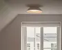 Rund, semi-plan loftlampe med glat hvid yderside, varmtonet inderskærm og et blødt lys nedad.