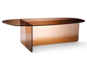 Moderne sofabord med en slank, oval bordplade og vinklet base, alt lavet af tonet glas i en varm ravfarve. Bordet har et minimalistisk design med rene linjer og reflekterende overflader, hvilket giver det et moderne og elegant udtryk. Glasmaterialet skaber en let og luftig fornemmelse, mens farven tilføjer et strejf af sofistikation.