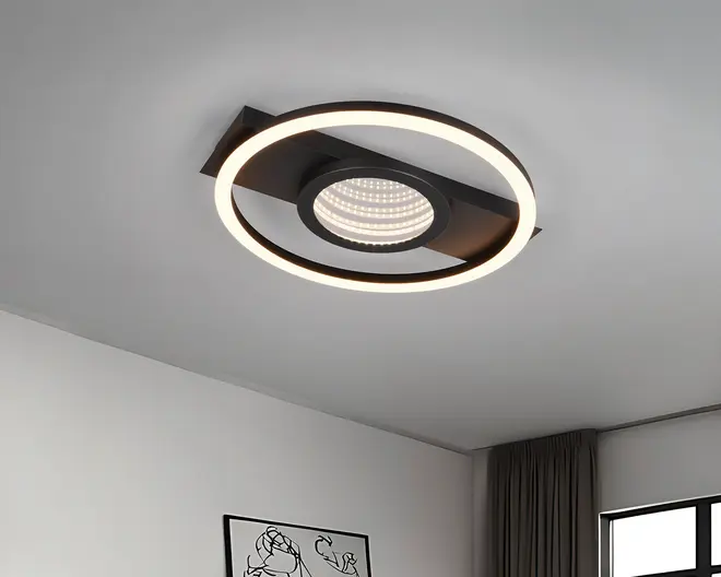 Loftmonteret lampe med et moderne, geometrisk design. Lampen har en cirkulær LED-ring, der udsender et blødt og jævnt lys, og en central skive med et gitter af mindre LED-lys for ekstra belysning. Lampen er mat sort og har en rektangulær base, der fastgøres til loftet, hvilket giver et stilfuldt og nutidigt udtryk.
