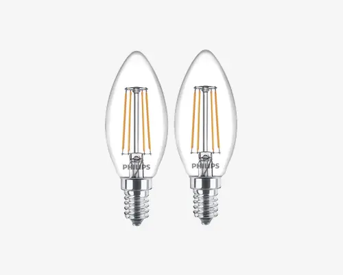 Sæt med to klare, stearinlysformede LED-pærer med synlige gule filamenter indeni. Hver pære har en blank sølvfarvet skruefatning og et gennemsigtigt glas, så de indvendige komponenter er synlige. Pærerne har Philips-logoet tæt på soklen.