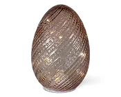 Dekorativt objekt formet som et æg, lavet af gennemsigtigt glas med et tekstureret, spiralformet mønster. Glasset har en let metallisk eller reflekterende overflade, og små varme hvide LED-lys er synlige indeni, hvilket skaber en blød, glødende effekt. Overfladen har forhøjede riller og udskæringer, der forstærker lysspredningen.