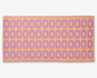 Rektangulært måtte med et gentagende mønster af lilla ovale former arrangeret i rækker på en ferskenfarvet baggrund. Måtten har en tekstureret overflade og en ferskenfarvet kant rundt om kanterne.