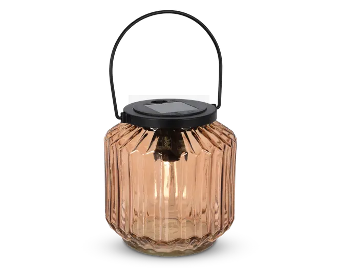 En lanterne med en rillet, ravfarvet glasbeholder og et sort metalhåndtag. Toppen har et solpanel, hvilket indikerer, at den er solcelledrevet. Glasset har et facetslebet design, der giver et dekorativt og elegant udseende.