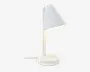 En moderne, minimalistisk lampe med mat hvid finish. Lampen har en konisk lampeskærm, der er vinklet nedad, fastgjort til en lige, lodret stang og en rund, solid fod. Der er en synlig ledning, der går ud fra foden, og lyset spredes blødt ud under skærmen, hvilket gør lampen velegnet til skrivebord eller natbord.