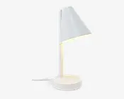 En moderne, minimalistisk lampe med mat hvid finish. Lampen har en konisk lampeskærm, der er vinklet nedad, fastgjort til en lige, lodret stang og en rund, solid fod. Der er en synlig ledning, der går ud fra foden, og lyset spredes blødt ud under skærmen, hvilket gør lampen velegnet til skrivebord eller natbord.