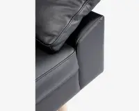 Nærbillede af et sofahjørne med sort tekstureret læderbetræk, en blød sædepude, en matchende ryghynde og en polstret armlæn. Sofaen har lyse træben, som kan ses nederst.