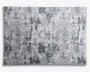Rektangulært tekstil med et moderne abstrakt mønster i forskellige grå nuancer, der har et slidt og tekstureret udtryk. Designet består af uregelmæssige felter og penselstrøgslignende markeringer, hvilket giver et moderne og alsidigt udseende, der passer til mange indretninger.