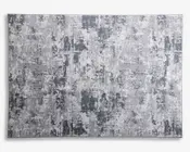 Rektangulært tekstil med et moderne abstrakt mønster i forskellige grå nuancer, der har et slidt og tekstureret udtryk. Designet består af uregelmæssige felter og penselstrøgslignende markeringer, hvilket giver et moderne og alsidigt udseende, der passer til mange indretninger.