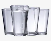 Sæt med fire klare, cylindriske drikkeglas med let konisk form, bredere foroven og smallere forneden. Glassene har en glat overflade og en tyk, solid bund for stabilitet. Ét glas er fyldt med vand, mens de tre andre er tomme.