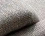 Nærbillede af et grå-beige vævet stof med en blød, nubret bouclé-lignende struktur og tykke polstrede kurver.