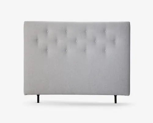 Rektangulært polstret sengegærde i lysegråt stof med et gitter af jævnt fordelte, stofbetrukne knapper for et tufted udseende. Overfladen er glat med en diskret tekstur, og sengegærdet står på to slanke, mørke ben.