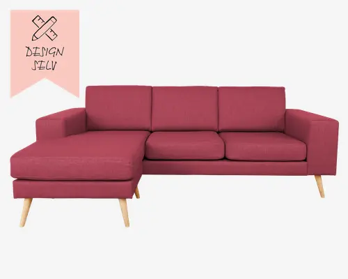 Moderne L-formet sofa betrukket med et støvet rosa stof. Sofaen har tre siddehynder og tre ryghynder for god komfort. Venstre side har en udvidet chaiselong, perfekt til afslapning. Sofaen har lige armlæn og står på skrå, lyse træben, hvilket giver et skandinavisk udtryk. Stoffet ser tæt vævet ud, og designet er minimalistisk og funktionelt.