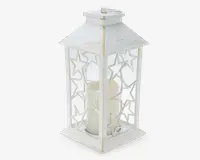 En dekorativ lanterne med hvid, slidt finish og glasruder indrammet af metaludskæringer i stjerneform. Lanternen har firkantet bund og pyramideformet top med et lille rundt håndtag. Indeni står et hvidt bloklys. Designet giver et rustikt og vintage udtryk, velegnet til både indendørs og udendørs brug.