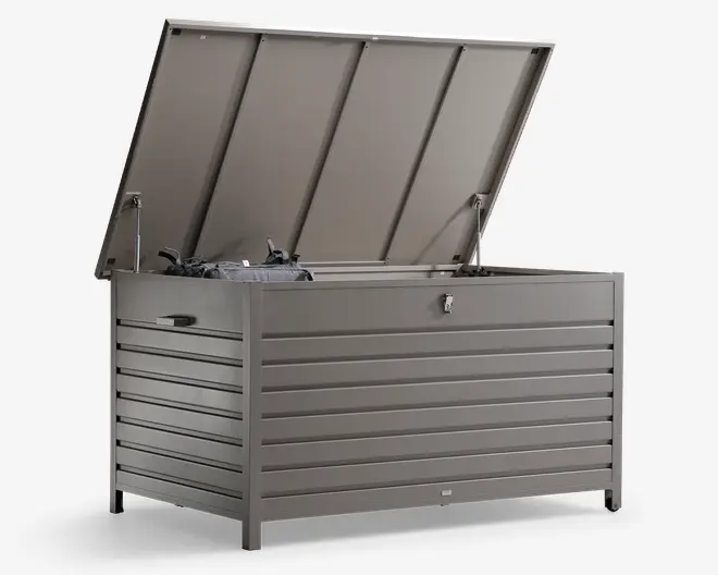 Stor udendørs opbevaringskasse med vandret lameldesign, fremstillet af holdbart metal i mat grå finish. Låget er åbent og afslører et rummeligt indre med vejrbestandig tætning og gasdæmpere for nem åbning. Kassen har en låsbar lås på fronten for sikkerhed samt integrerede sidehåndtag for nem flytning. Velegnet til opbevaring af havemøbler, hynder eller udendørsudstyr.
