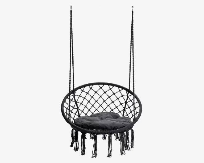 Rund hængestol med sort flettet ramme og dekorative macramé frynser nederst. Sædet har en tyk, polstret mørkegrå pude for ekstra komfort. Ryglænet har et åbent, geometrisk mønster, og stolen hænger i to solide reb.