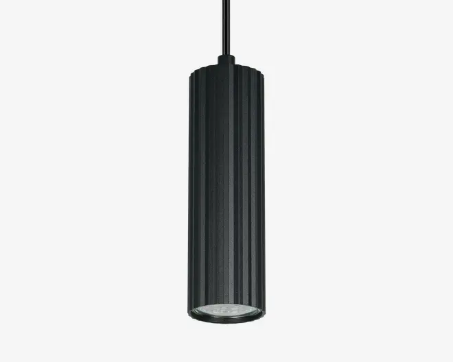 En cylindrisk pendellampe med lodrette riller og mat sort overflade. Lampens krop er aflang og har en klar linse i bunden, som giver et fokuseret nedadgående lys. Lampen hænger i en tynd, lige ledning og har et moderne, minimalistisk udtryk.