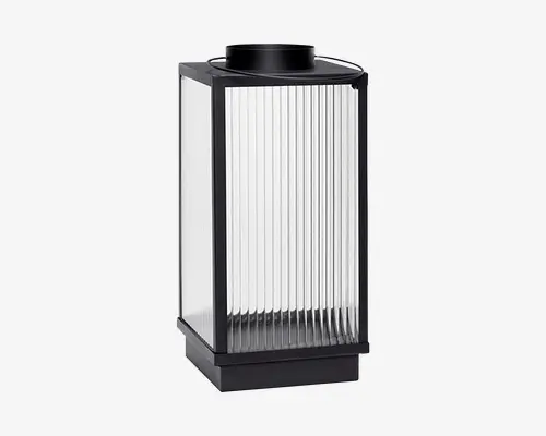 Rektangulær lanterne med sort metalramme og klare, lodret riflede glasplader på alle sider. Top og bund er i solid sort, hvilket giver et moderne og minimalistisk udtryk. Det riflede glas spreder lyset blødt, og lanternen har en flad top med en lille cirkulær åbning, sandsynligvis til at placere et stearinlys eller en lyskilde indeni.