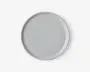 Rund tallerken med en glat, mat lysegrå overflade og en let forhøjet kant. Designet er minimalistisk og moderne uden mønstre eller dekorationer.
