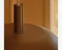 Nærbillede af en varm brun, rund lampe med en lodret cylindrisk topdel og en hvid ledning, der går ud fra toppen.