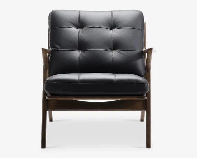 Denne stol har et elegant, moderne design med en sort, polstret læderhynde på både sæde og ryglæn. Hynden er opdelt i firkantede sektioner med synlige syninger, hvilket giver et blødt og komfortabelt udtryk. Stellet er lavet af mørkt træ med let buede armlæn og solide ben, hvilket giver stolen et stilfuldt og holdbart udseende.