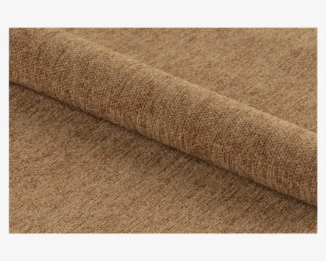 Nærbillede af et rullet stykke stof i en varm, mellembrun farve. Stoffet har en blød, tekstureret overflade med et diskret, ensartet vævemønster, hvilket giver det et hyggeligt og let plysset udseende. Materialet ser tykt og holdbart ud, velegnet til polstring eller boligindretning.