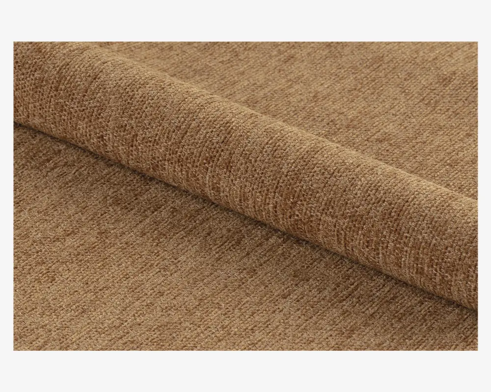 Nærbillede af et rullet stykke stof i en varm, mellembrun farve. Stoffet har en blød, tekstureret overflade med et diskret, ensartet vævemønster, hvilket giver det et hyggeligt og let plysset udseende. Materialet ser tykt og holdbart ud, velegnet til polstring eller boligindretning.