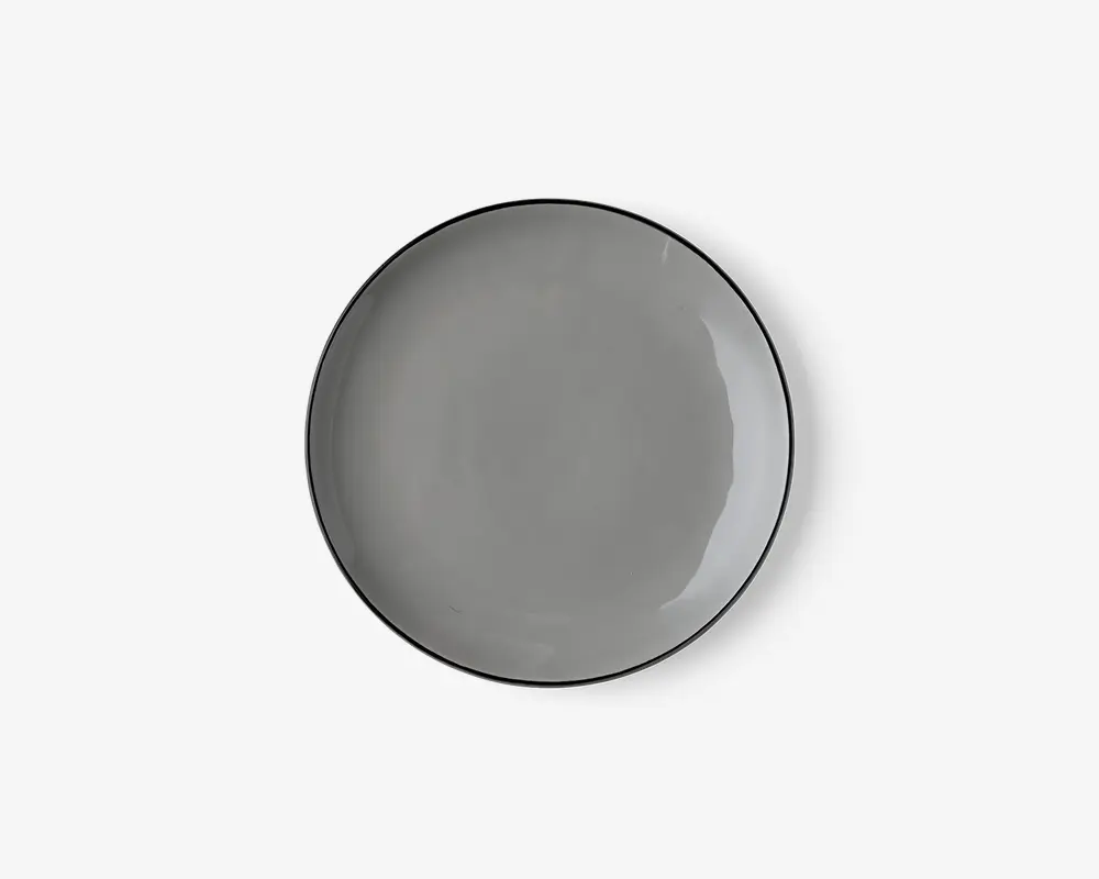 Rund tallerken med en glat, blank overflade i ensfarvet grå. Tallerkenen har en let forhøjet kant og et minimalistisk design, der passer til moderne borddækning.