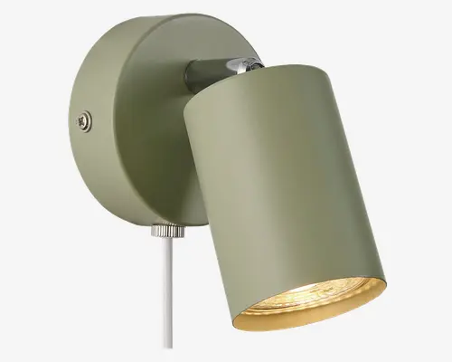 Væghængt spotlampe med mat olivengrøn finish. Det cylindriske lampehoved kan justeres, så lyset kan rettes efter behov. Lampen har en rund base med synlig skrue og en træksnor til nem tænd/sluk-funktion. Indersiden af lampehovedet er guldfarvet, hvilket giver et varmt lys.