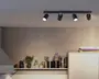 Sort loftmonteret lysbalk med fire justerbare spot-hoveder, hvoraf to er tændt, vist mod en neutral væg og loft.