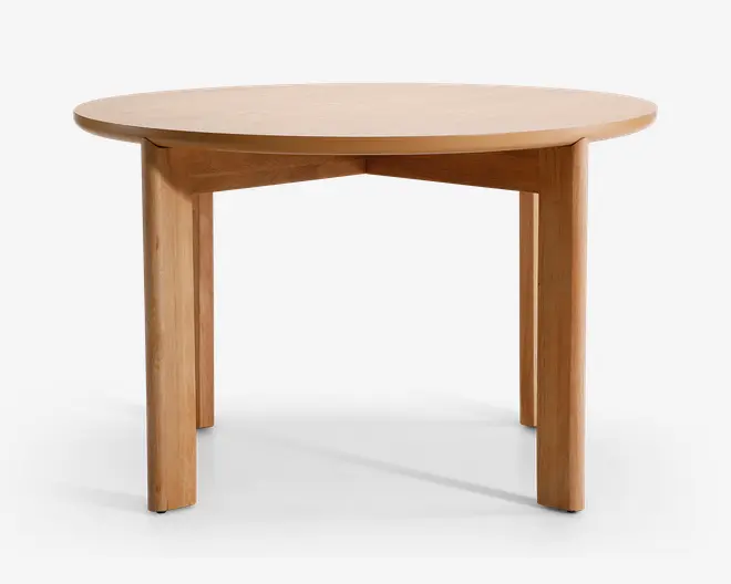 Rundt bord i træ med en glat, lys naturfinish. Bordpladen har en let skrå kant, og bordet står på fire solide, lige ben. Designet er minimalistisk og moderne med rene linjer og synlig træstruktur.