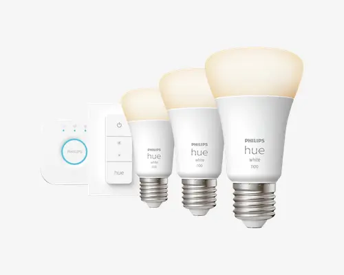 Sættet indeholder tre smarte LED-pærer med mat hvid overflade og standard skruefatning samt en trådløs dæmperkontakt og en smart hub. Pærerne er mærket "Philips Hue White 1100" og er designet til justerbar lysstyrke. Dæmperkontakten har fire knapper til tænd, sluk og lysstyrkekontrol. Smart-hubben har en rund knap og indikatorlys for tilslutning.