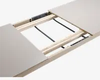 Nærbillede af et bord med udtræksmekanisme, hvor to bordplader er adskilt for at vise de indvendige træskinner og metalbeslag. Designet gør det muligt at tilføje en ekstra plade for at forlænge bordet. Bordpladen har en glat, lys overflade, og rammen er lavet af lyst træ.