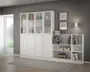 Et moderne, hvidt opbevaringsmøbel med en kombination af lukkede skabe, vitrinesektioner med glaslåger og åbne hylder. Den øverste del har fire høje rum med glaslåger, hvor der vises dekorative genstande og opbevaringskasser. Den nederste del består af lukkede skabe med enkle, runde greb. Til højre er der åbne hylder med bøger, to beige opbevaringskasser og flere dekorative elementer. Møblet står op ad en grå væg med indrammet kunst og en lille lampe over hylderne. Designet er slankt og minimalistisk, velegnet til et moderne hjem.
