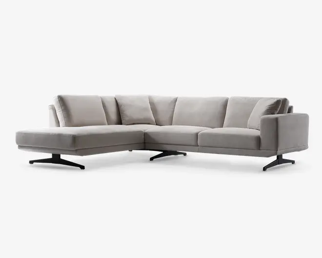 En moderne L-formet sofa med lysegråt betræk, brede og dybe sæder samt bløde ryghynder for ekstra komfort. Sofaen har rene, lige linjer og lavprofilerede metalben, hvilket giver et moderne udtryk. Venstre side har en chaiselong, der er ideel til afslapning eller at strække sig ud på.