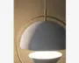 Nærbillede af en moderne pendellampe med en mat hvid, halvkugleformet skærm og en tilsvarende hvid, skålformet diffuser nedenunder. Lampen har en elegant bueformet ramme i messing eller guldmetal, som giver et stilfuldt udtryk. Lampen hænger fra en lodret stang, og designet er minimalistisk og nutidigt.