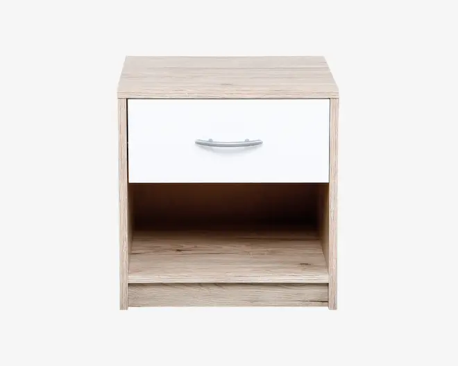 Rektangulært natbord med lyst trælook, der har en enkelt hvid skuffe med et buet sølvfarvet greb og en åben opbevaringshylde under skuffen. Designet er moderne og minimalistisk med rene linjer og en glat overflade.