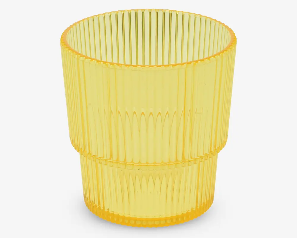 Et gennemsigtigt gult drikkeglas med lodret rillet tekstur. Glasset har en cylindrisk form, der bliver en smule smallere mod bunden, og har en markant vandret kant omkring midten, som deler det rillede mønster i to sektioner.