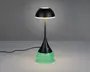 Moderne bordlampe med sort, kuppelformet skærm og en slank, central stang. Basen er konisk med en berøringsfølsom tænd/sluk-knap og har en glødende grøn, tekstureret overflade, der giver en dekorativ effekt. Lampen er tilsluttet med en synlig ledning.