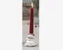 Et højt rødt stearinlys med lille flamme, sat i en hvid base formet som julemandens ansigt med rød nissehue og fyldigt hvidt skæg.