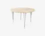 Rundt bord med en lys træbordplade og fire slanke, skråtstillede metalben i kromfinish. Bordpladen har en glat overflade med synlig træstruktur, og benene er let udadgående for stabilitet, hvilket giver bordet et moderne og minimalistisk udtryk.